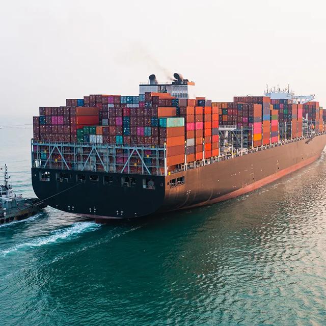 A large container ship navigates through the vast ocean, showcasing its impressive size against the blue waters.